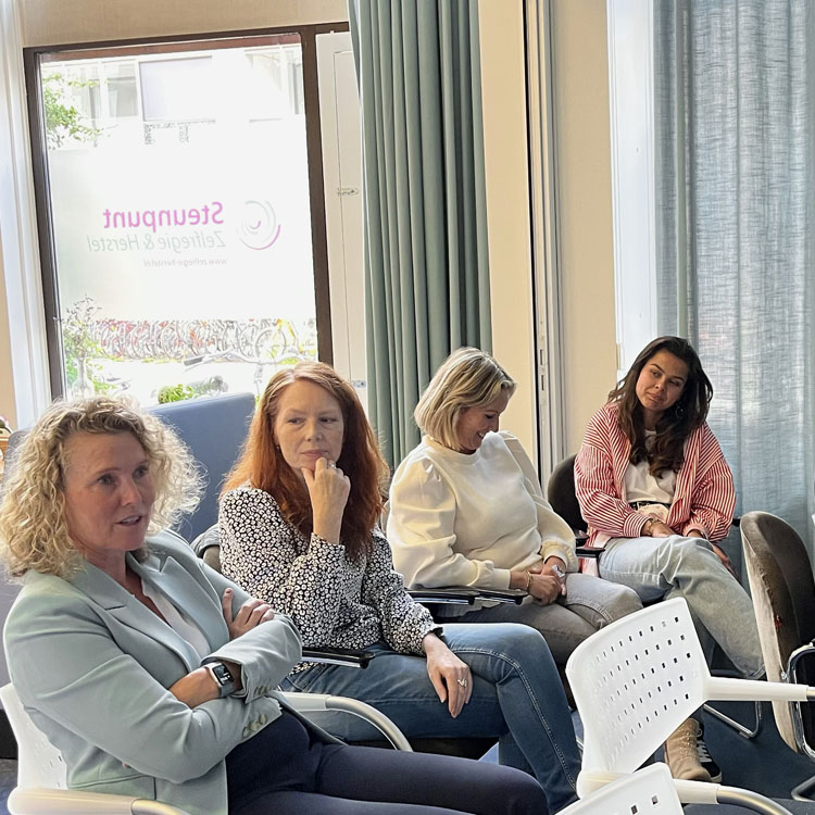 4 dames zittend in een groepsoverleg