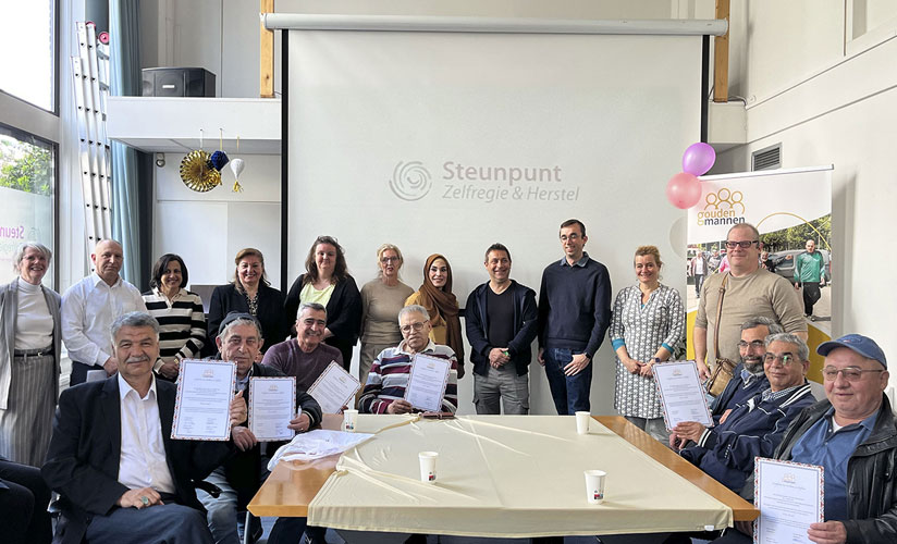 Een groep van 15 mensen in een ruimte die hun diploma laten zien.