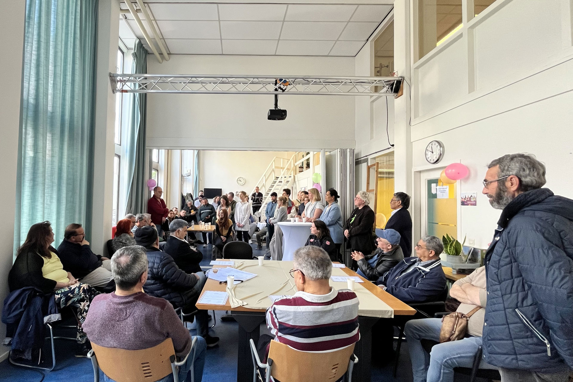 Groep deelnemers staand en zittend in een ruimte voor een presentatie.